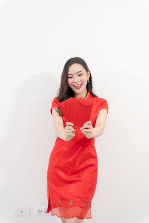 Happy Asian woman in traditional cheongsam making hand gestures isolated on white background. Happy Chinese New Year.の写真素材