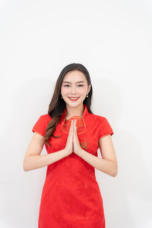 Happy Asian woman in traditional cheongsam making hand gestures isolated on white background. Happy Chinese New Year.の写真素材