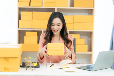 Asian woman using laptop with box, successful cheerful for online marketing packaging and delivery...