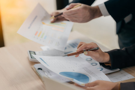 Business people discussing charts and graphs showing results of teamwork in a meeting to analyze financial reports, planning strategies, success.の写真素材