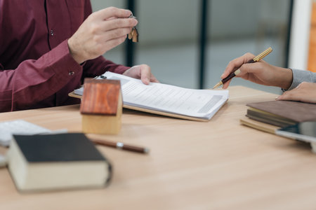 Real estate agents hand over the keys to clients after signing the contract and provide advice to...