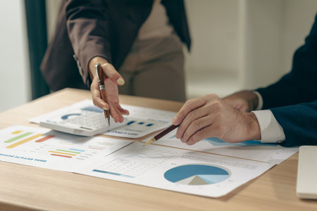 Business people discussing charts and graphs showing results of teamwork in a meeting to analyze financial reports, planning strategies, success.の写真素材
