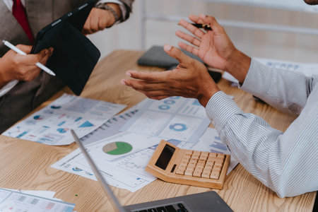 Group of business people discussing charts and graphs showing results of teamwork using laptops. Strategic planning and brainstorming. Colleagues.の写真素材