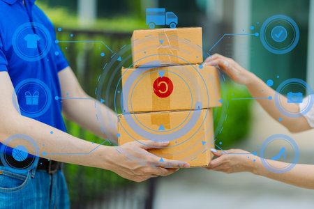 Delivery man wearing blue shirt is delivering packaged goods to young female customer at front door delivery conceptの写真素材