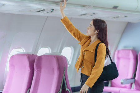 Businesswoman walking with luggage on airplane. Concept of business travel, transportation, aviation and tourism. Commercial airplane.の写真素材