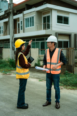 Asian male and female engineers and architects discuss at a construction site; professional...
