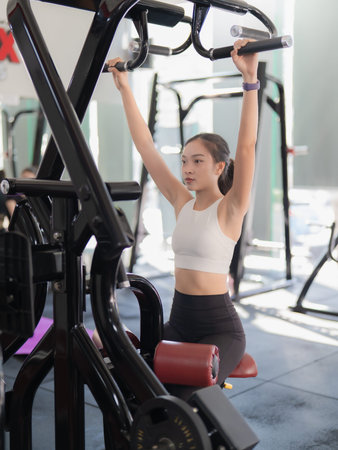 A beautiful Asian woman is working out in the gym, showcasing her strength and physical fitness for...