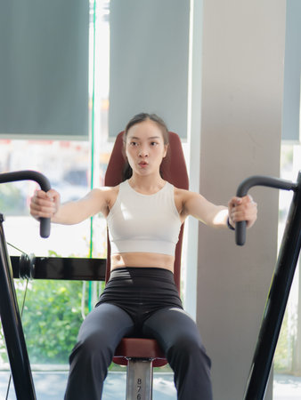 young asian woman working out on exercise bike in fitness gym.