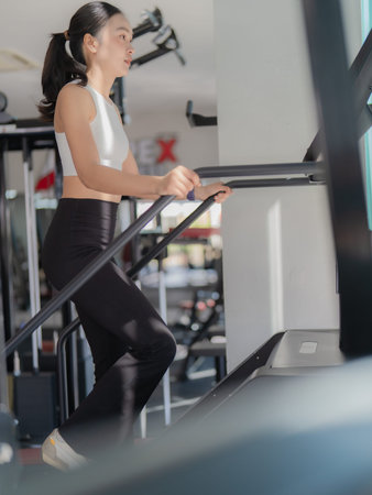 An Asian woman is exercising on an exercise bike in a gym.