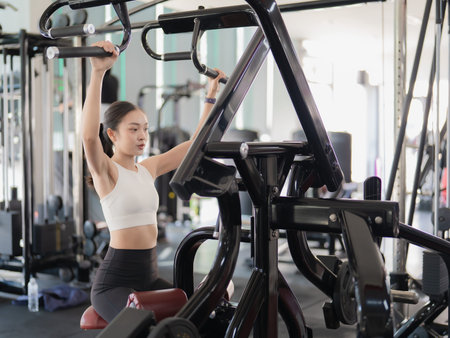 A beautiful Asian woman is working out in the gym, showcasing her strength and physical fitness for...