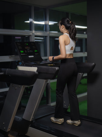 An Asian woman is exercising on a treadmill in a gym. Healthy lifestyle and weight loss.