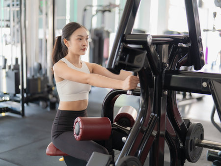 A beautiful Asian woman is working out in the gym, showcasing her strength and physical fitness for...