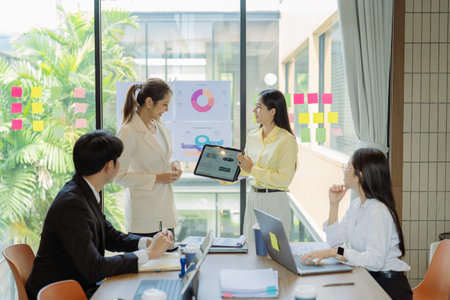 A business group meeting is underway, discussing charts and graphs that illustrate the results of...
