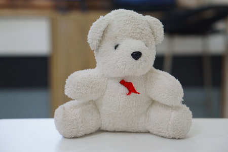 Teddy bear with red ribbon on white table in living room.の写真素材