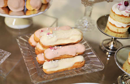 Close up of small desserts eclairs, the plates and table decorated for wedding ceremony