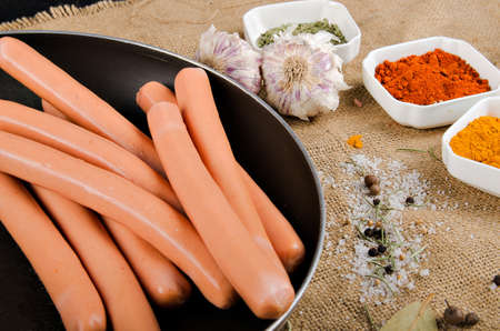 the photograph shows sausages in a pan next to some spicesの写真素材