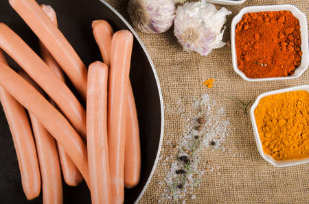 the photograph shows sausages in a pan next to some spicesの写真素材