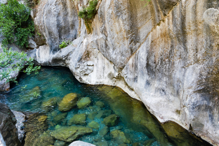 Pristine waters of Sapadere canyon steep wall like slopes of Taurus mountains and stones visible on bottomの写真素材