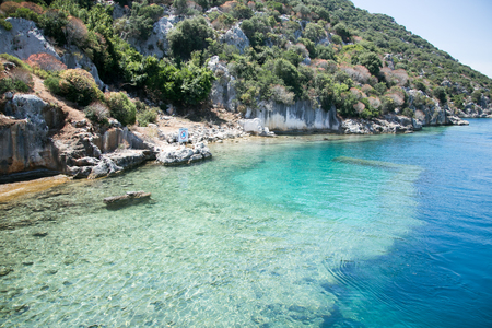 sunken city of Kekova in bay of Uchagiz view from sea in Antalya province of Turkey with turqouise sea rocks and green bushes with remains of ancient city visible under water.の写真素材