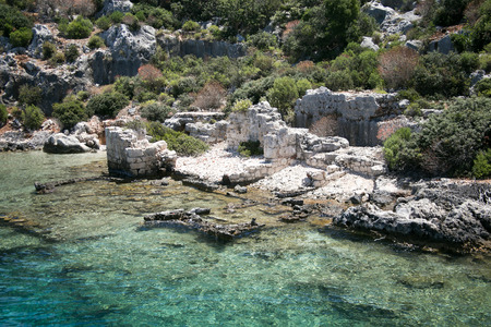 sunken city of Kekova in bay of Uchagiz view from sea in Antalya province of Turkey with turqouise sea rocks and green bushes with remains of ancient city visible under waterの写真素材