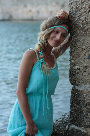 Young woman thinking and standing with blurred sea and medieval castle walls behindの写真素材