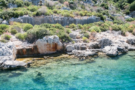 sunken city in bay view from sea in Antalya province of Turkey with turqouise sea rocks and green bushes with remains of ancient city visible under water.の写真素材