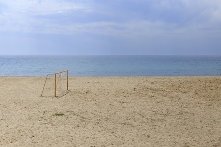 Yellow painted football gate at sandy beach against blue seaの写真素材