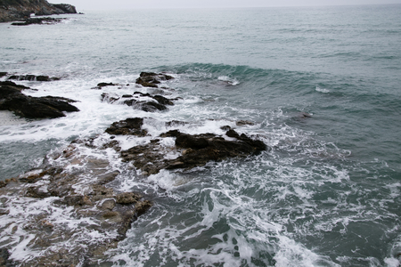 waves washing rocks shot on cloudy dayの写真素材