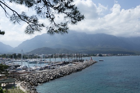 View of yacht marina and mountains with turqoise sea and cloudy skyの写真素材