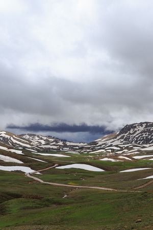 Vertical shot of landscape with moutnains covered by melting snowの写真素材