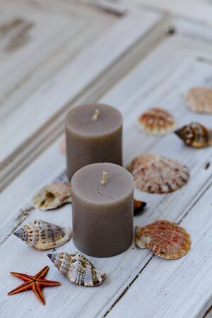 Two gray candles with seashells around over white rustic background shot with shallow depth of fieldの写真素材