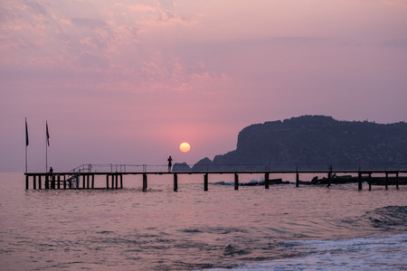Horizontal seascape with the pier, sea and castle rock of Alanya at sunsetの写真素材