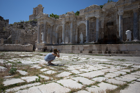 Woman traveller wearing long summer dress and hat photographing agora with marble columns and statues at ancient city of  Sagalassosの写真素材