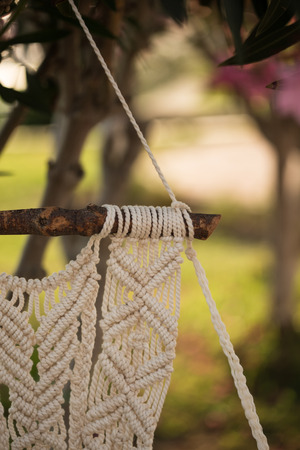 Closeup of macrame art hanging from the piece of driftwood, shot with shallow depth of fieldの写真素材