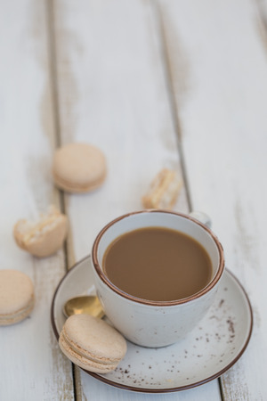 A cup of coffee, with golden tea spoon and a few pink macaroons. Vertical composition. Copy spaceの写真素材