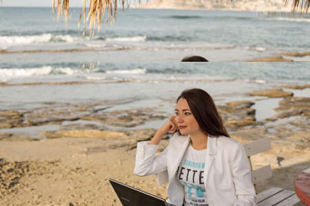 Freelancer woman working on her laptop by the sea. Copy space.の写真素材