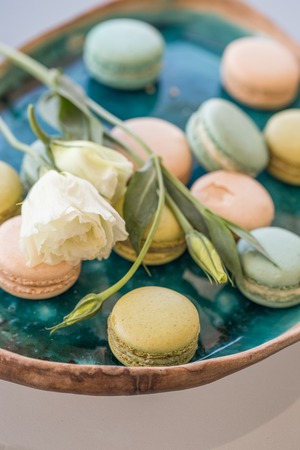 Pink and green macaroons and white lisianthus in a ceramic plateの写真素材