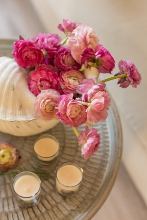 Pink ranunculus in a vase and three candles on metal rustic tray. Vertical composition.の写真素材