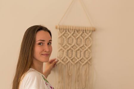Young and beautiful smiling macrame artist with her macrame wall artの写真素材