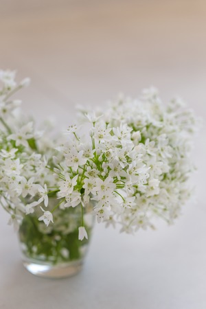A bouquet of white spring flowers in a glass vase. Vertical composition. Copy space.の写真素材