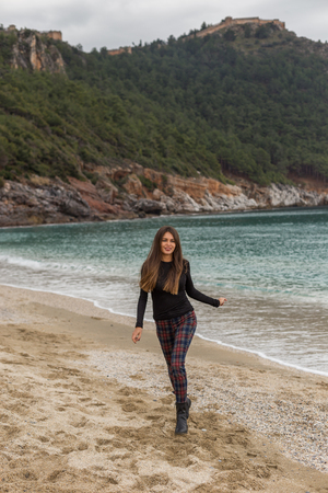 beautiful fit female wearing black sweater and checked trousers running at winter beachの写真素材