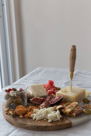 Mediterranean cheese plate with figes and olives placed on a round half marble half wooden cheese board. Vertical composition. Copy space.の写真素材