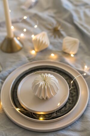 Vertical shot of monochrome Christmas table setting with Christmas lights and white origami decorationsの写真素材