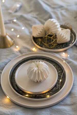 Vertical shot of monochrome Christmas table setting with Christmas lights and white origami decorationsの写真素材