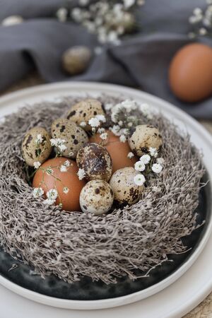 Vertical image of easter table styling with scandinavian style tableware, artificial nest and chickenの写真素材