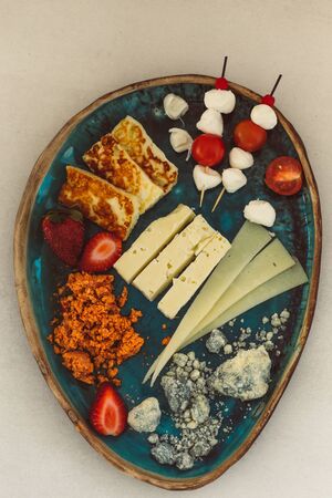 Upper view image of the Mediterranean cheese platter with variety of cheese, strawberries and cherry tomatoesの写真素材