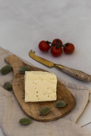 Slices of white cheese on a wooden cheeseboard served with greenの写真素材
