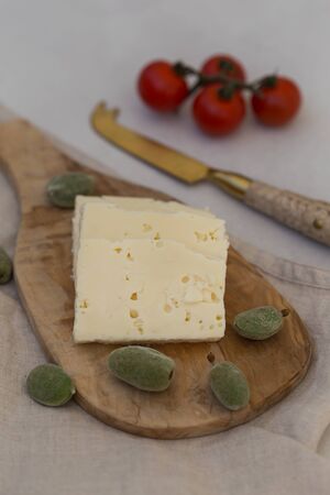 Slices of white cheese on a wooden cheeseboard served with greenの写真素材