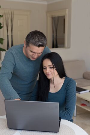 Couple in matching outfites working from home using black laptopの写真素材