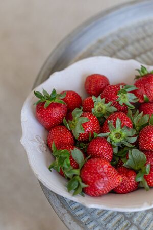 Strawberries in a white rustic bowl on a metal trayの写真素材